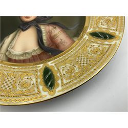 Late 19th century cabinet plate in the manner of Vienna, finely painted with quarter length portrait of the Queen of the Roses, signed Wagner, within elaborate gilt foliate scroll panelled border on white ground interspersed with raised green oval motifs painted to mimic marble, with impressed and red beehive marks, titled Königin der Rosen no 10171 and stamped Germany, D23.5cm