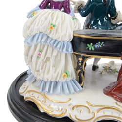 German lace figure group, modelled as a piano recital, the female figures with lace skirts and trimmed gowns, the male figures with lace cuffs and cravats, upon a gilt scrolling base, H22.5cm W33cm 