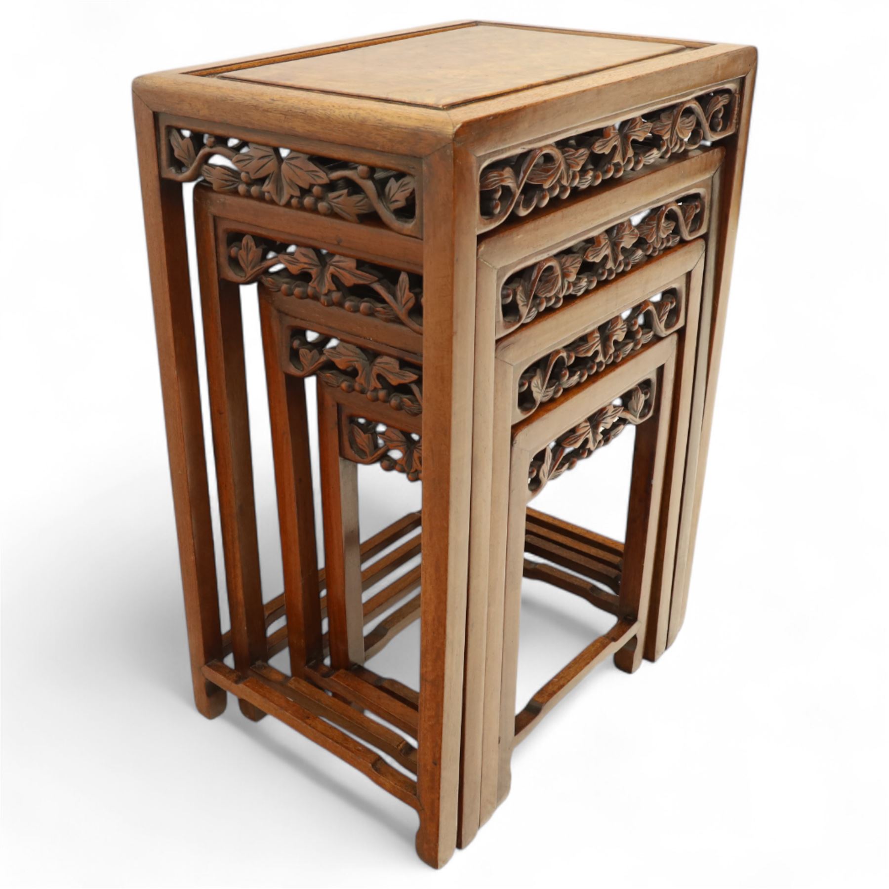 Early 20th century Chinese style hardwood quartetto nest of tables, each with panelled top and carved and pierced vine motif frieze, on square legs united by straight stretchers