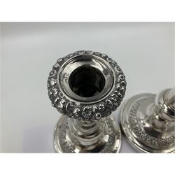 Four George III silver candlesticks, each upon knopped stem and weighted circular stepped foot, the foot and removable sconce repousse decorated with a band of flower heads, hallmarked to sconce and foot Thomas & John Settle, Sheffield 1820, H17.5cm