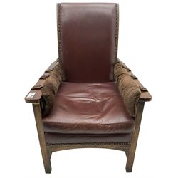 1930's hardwood-framed reclining armchair, upholstered in brown studded leather, on square supports united by horizontal and vertical stretchers, arched middle rail