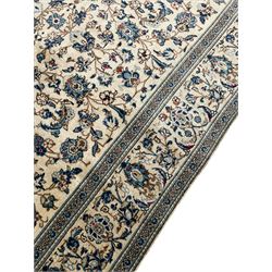 Persian Kashan ivory ground rug, the field decorated with trailing branches with leaves and palmettes, similar scrolling border, within floral pattern guard stripes 