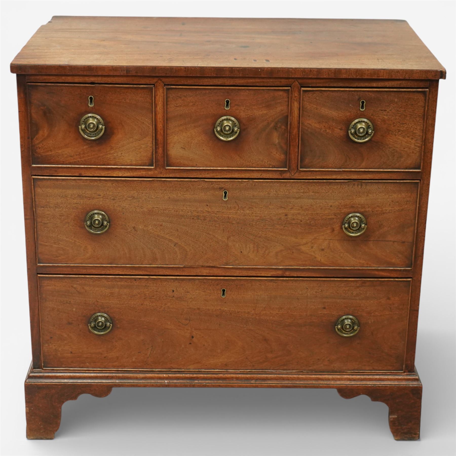 Small 19th century mahogany chest of drawers, rectangular top with moulded edge over three short and two long drawers, the drawers fitted with brass ring handles and key escutcheons, raised on shaped bracket feet