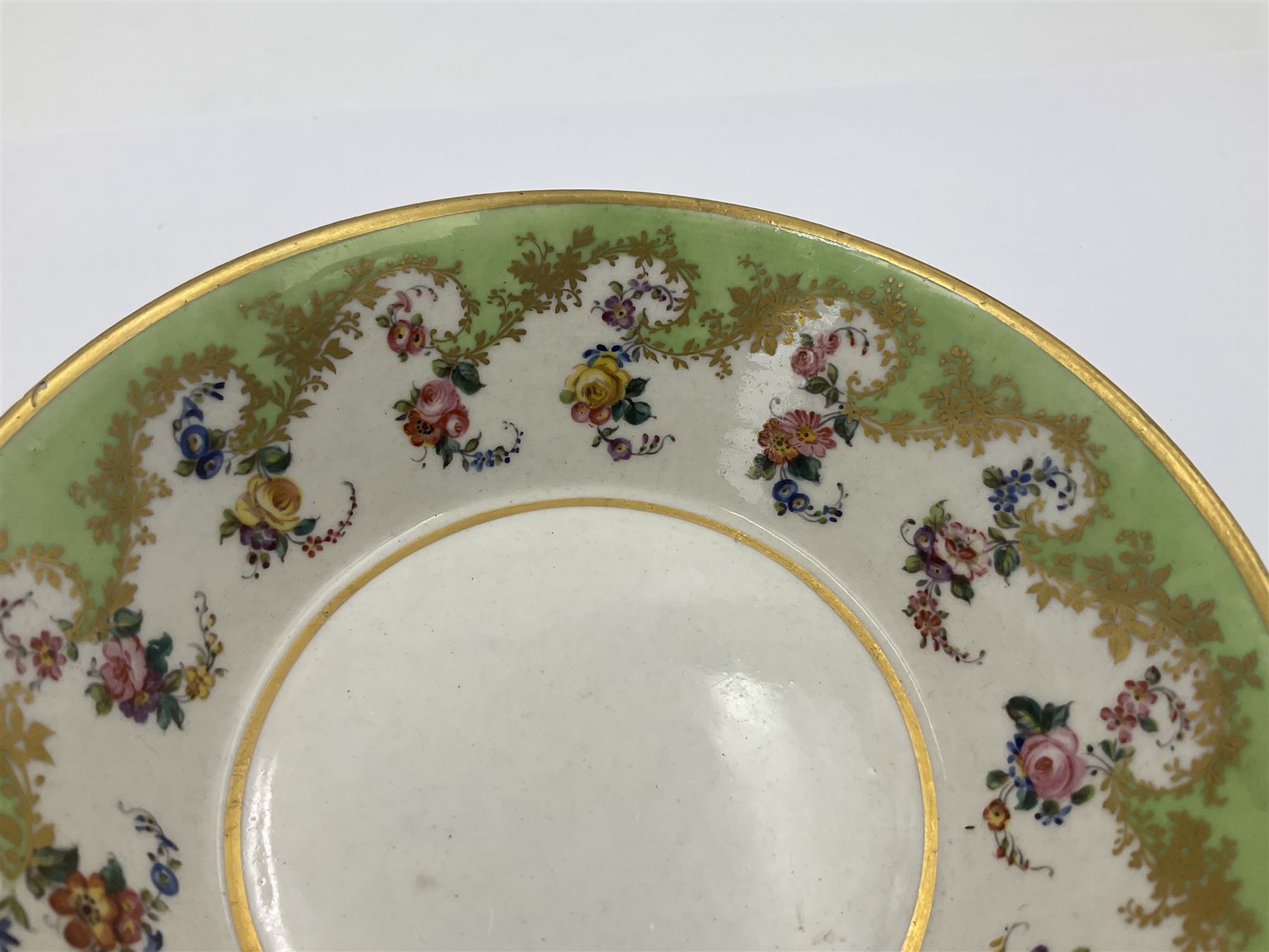 Sèvres soft paste porcelain coffee can and saucer with date code for 1754, painted and gilded with flowers, dangling from the shaped green border, interlaced LL monogram enclosing the date letter A above painters mark for Dodin, coffee can H7cm, saucer D14.5cm