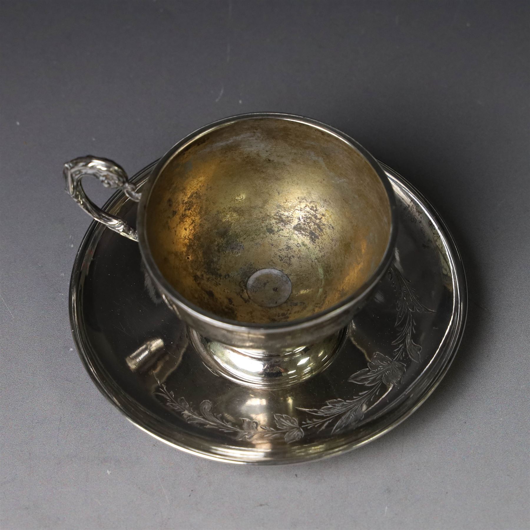 German silver cup and saucer, both with engraved foliate decoration, stamped 800, the saucer with crescent and crown mark