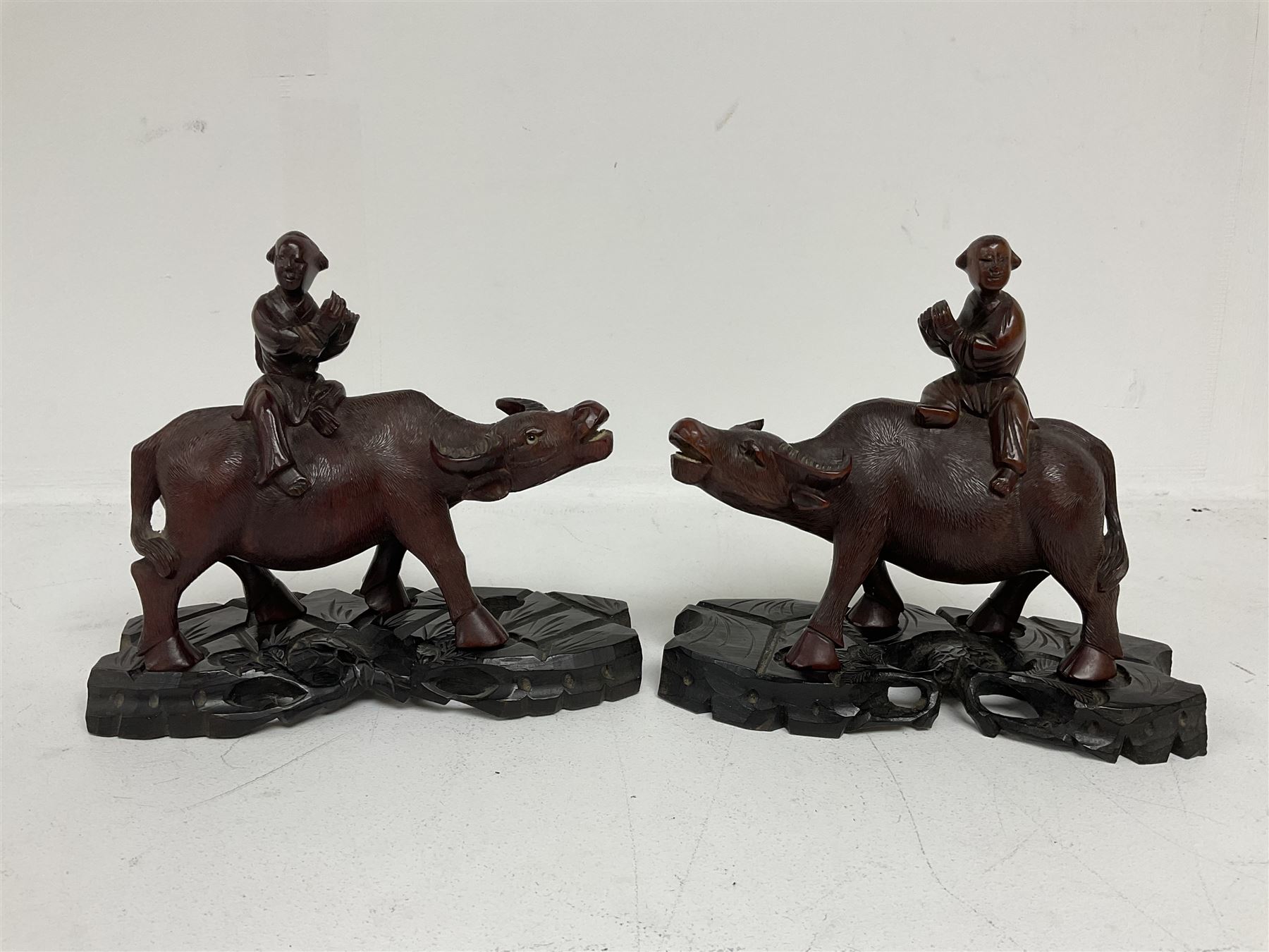 Pair of Chinese hardwood figures of farmers riding water buffalo, on stands, H19cm