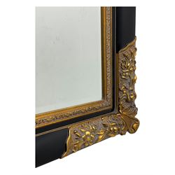 Early 20th century wall-hanging mirror, rectangular bevelled mirror plate within ebonised frame, gilt mounts to the corners carved with floral motifs 