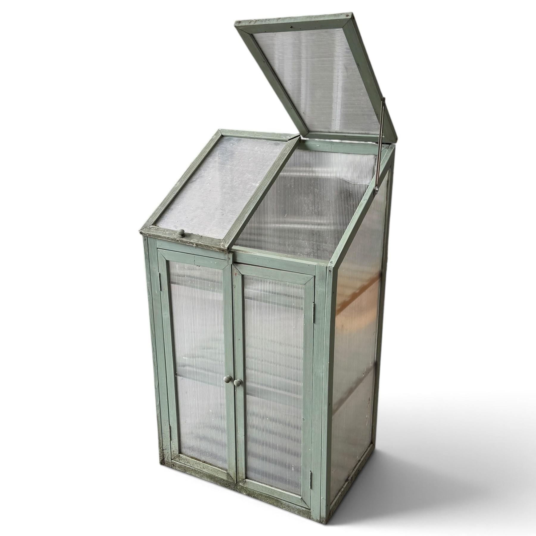 Three green-painted timber cold-frame greenhouses or growhouses, each with twin hinged sloping polycarbonate lids above a pair of panelled doors enclosing slatted shelves