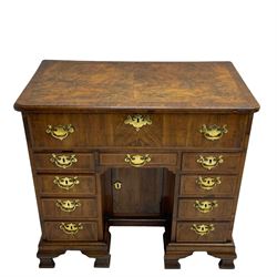 Early 18th century Queen Anne figured walnut kneehole desk with secretaire drawer, moulded and book matched top with walnut band, the top drawer with fall front enclosing small drawers and pigeon holes, fitted with nine drawers and central recessed cupboard, on ogee bracket feet