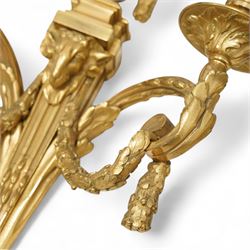 Pair of 19th-century Louis XVI-style ormolu rams-headed two-light wall appliques, the arms joined by a garland of laurel leaves, the half fluted stem surmounted by a vase with laurel garland, wired for electricity 