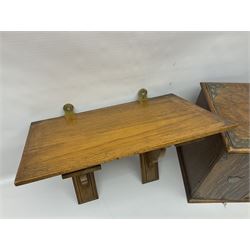 Early 20th century oak smokers cabinet, with brass shield shaped mounts, opening to reveal a compartmentalised interior with three drawers, pipe rack and tobacco jar, together with a small wooden shelf, smokers cabinet H28.5cm