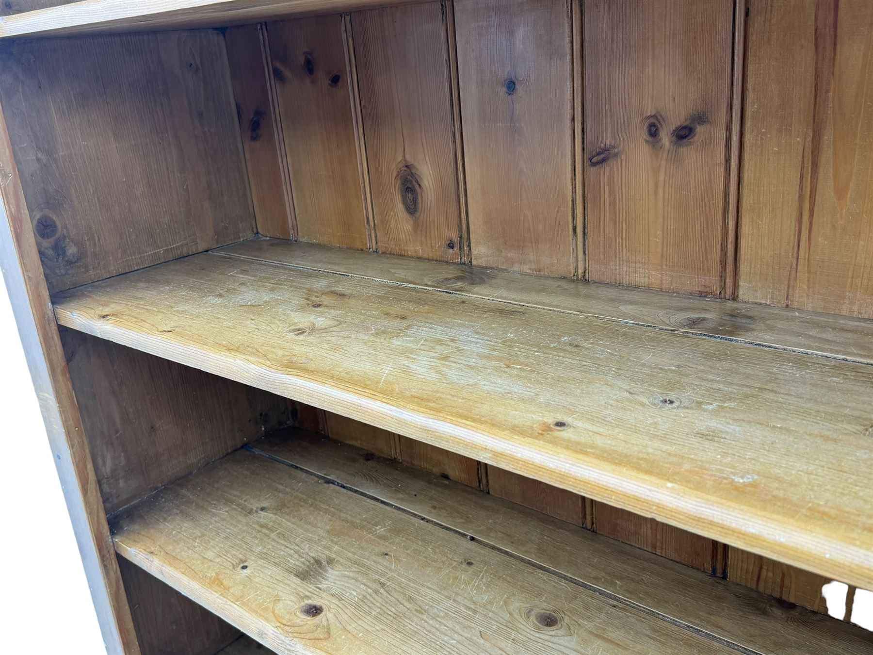 Early 20th century pine kitchen dresser, featuring a hutch with arched top over three open shelves, the base with five drawers over three cupboard doors, turned column supports flanking the doors, scalloped apron base with bracket feet