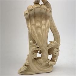 A large Japanese carved ivory okimono, modelled as a figure stood upon one leg with arms outstretched, upon a five headed serpent emerging from waves, H30cm.