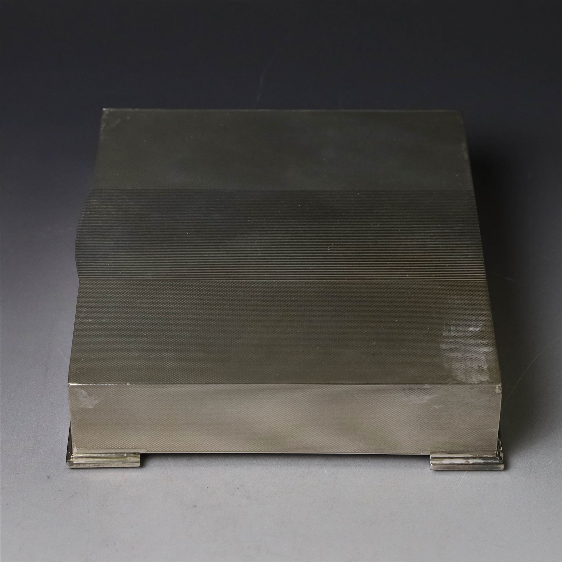 1960s silver mounted cigarette box, of rectangular form with engine turned decoration, upon four bracket feet, with presentation engraving to interior lid reading  'British Aircraft Corporation (Operating) Limited Commemorating the Queen's Award to Industry 1967, hallmarked James Geraghty, Birmingham 1965, with retailers mark for Asprey, W16.5cm, H4.5cm