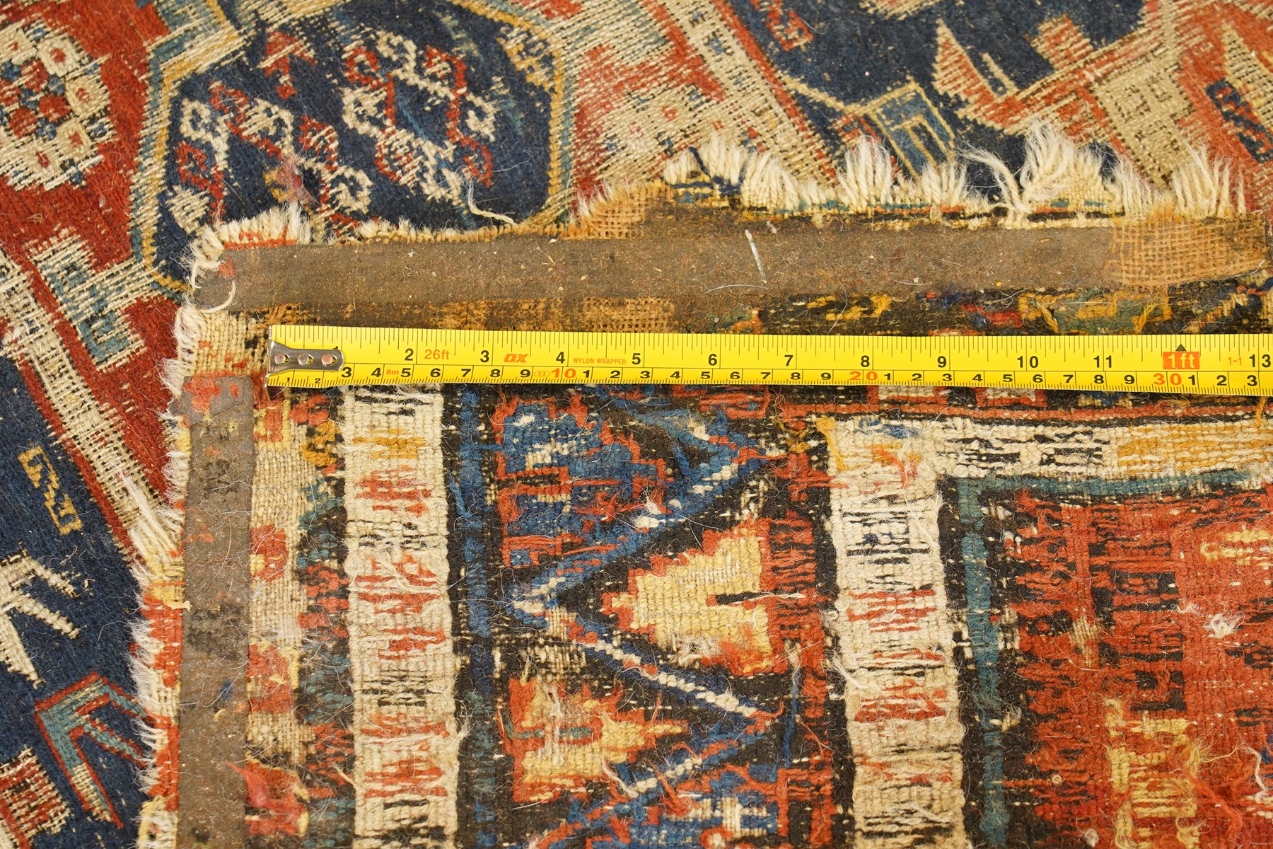 Antique Caucasian crimson ground carpet. the field decorated with three geometric indigo medallions with surrounding geometric motifs and guard lines