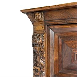 Late 17th century Flemish/Dutch rosewood and oak ‘Zeeuwse Kast’ or cupboard, projecting cornice carved with three putti masks, the uprights carved with lion masks over ribbons, flower heads and foliage, enclosed by four geometric panelled doors, lower central upright carved with flower head over foliate ribbon with bird among foliage, the escutcheon hidden by swivel berry carved cover, interior fitted with shelves, two drawers and shallow hinged cupboard, on two large turned and ebonised feet, circa 1680