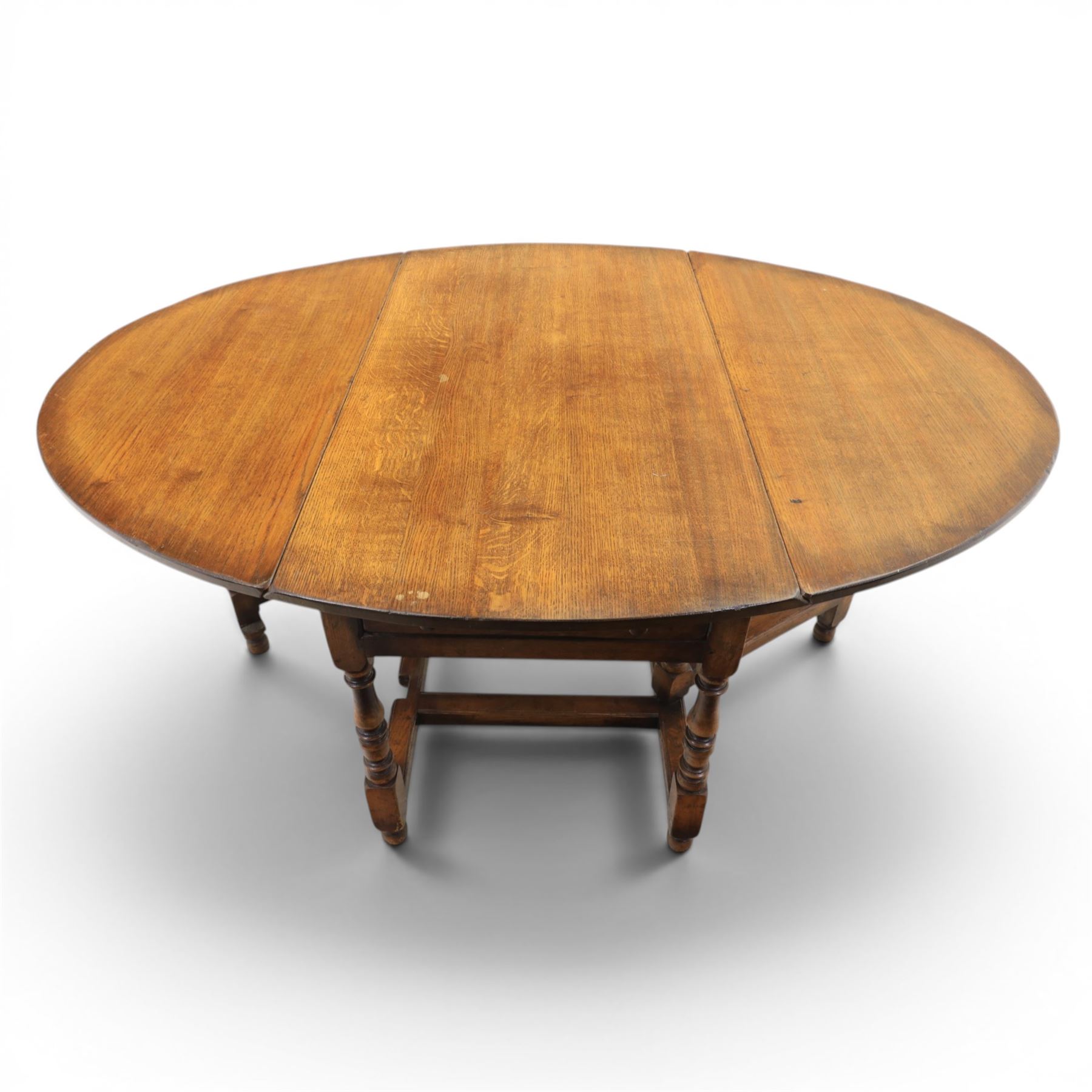 Titchmarsh & Goodwin - 18th century design oak oval drop-leaf dining table with leather dining chairs, the table with drop leaves forming an oval top extending to 180cm, with drawer to either side, raised on turned supports with gateleg, the chairs comprising two carvers in tan leather and two side chairs in green and tan leather backs, brass studded trim with turned uprights and stretchers