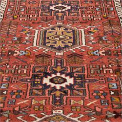 North West Persian Heriz hand-knotted runner, terracotta field decorated with a series of large angular medallions with stylized geometric motifs, surrounded stepped devices, and stylized trees within narrow geometric border, and polychromed edge, cotton fringe ends 