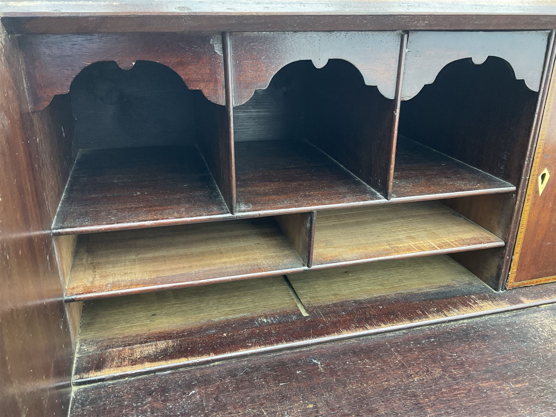 George III mahogany bureau, the conch inlaid fall front enclosing pigeon holes, shelves and central cupboard with inlaid flower motif, four graduating cock-beaded drawers below each with brass handles, lower moulded edge over shaped bracket feet