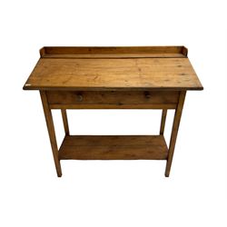 Stained pine clerks desk or table, raised back and sloped writing surface over single fall-front cupboard, raised on square supports united by under-tier