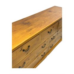 Pine dresser, rectangular top above seven drawers, with two smaller drawers over five larger drawers, all fitted with cast metal handles, raised on a shaped plinth base

