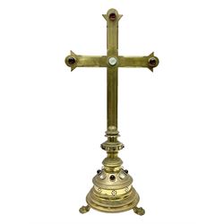 Brass alter cross, decorated with glass cabochons, upon a acicular stepped base and three claw feet, H73cm 