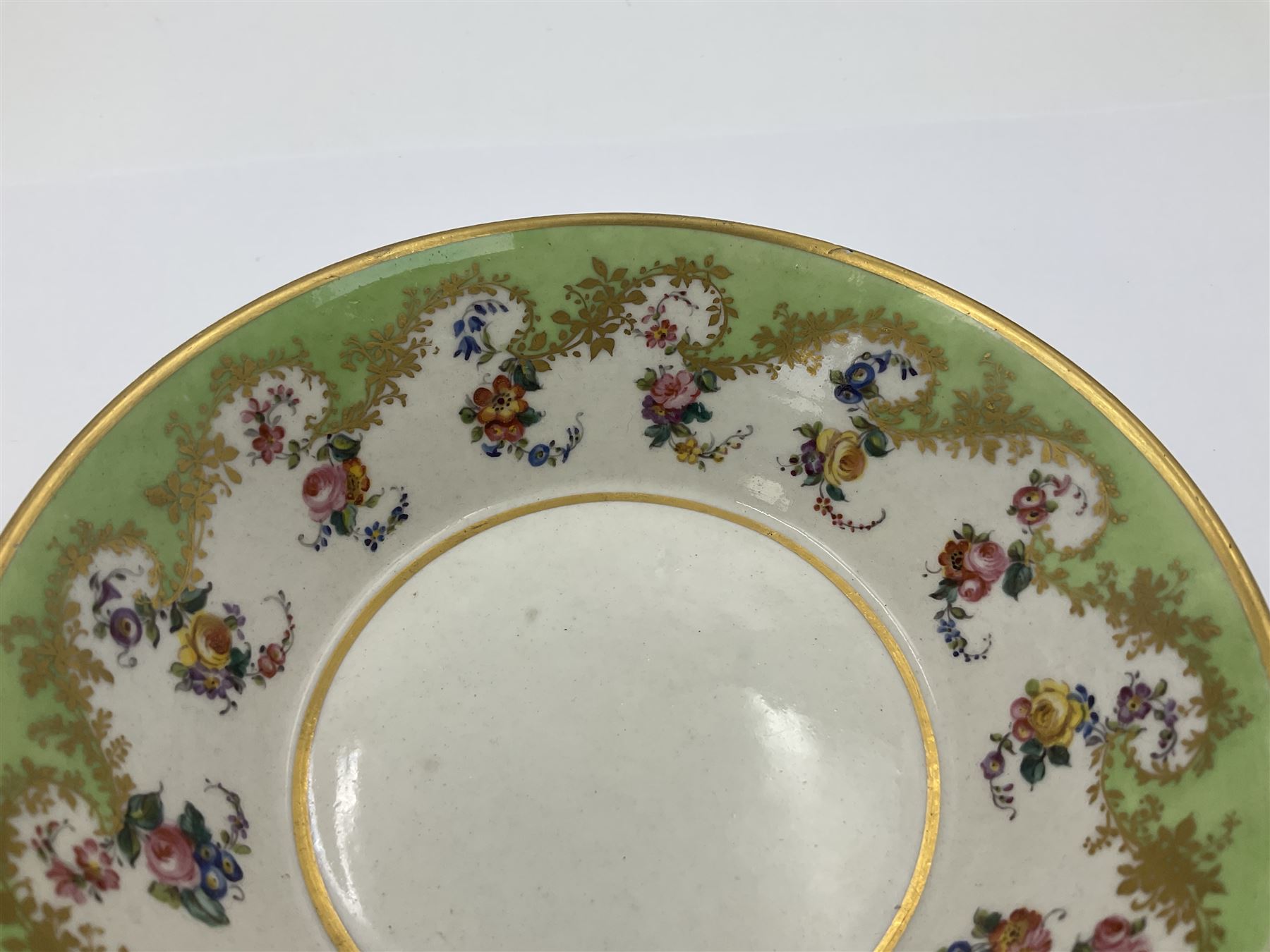 Sèvres soft paste porcelain coffee can and saucer with date code for 1754, painted and gilded with flowers, dangling from the shaped green border, interlaced LL monogram enclosing the date letter A above painters mark for Dodin, coffee can H7cm, saucer D14.5cm