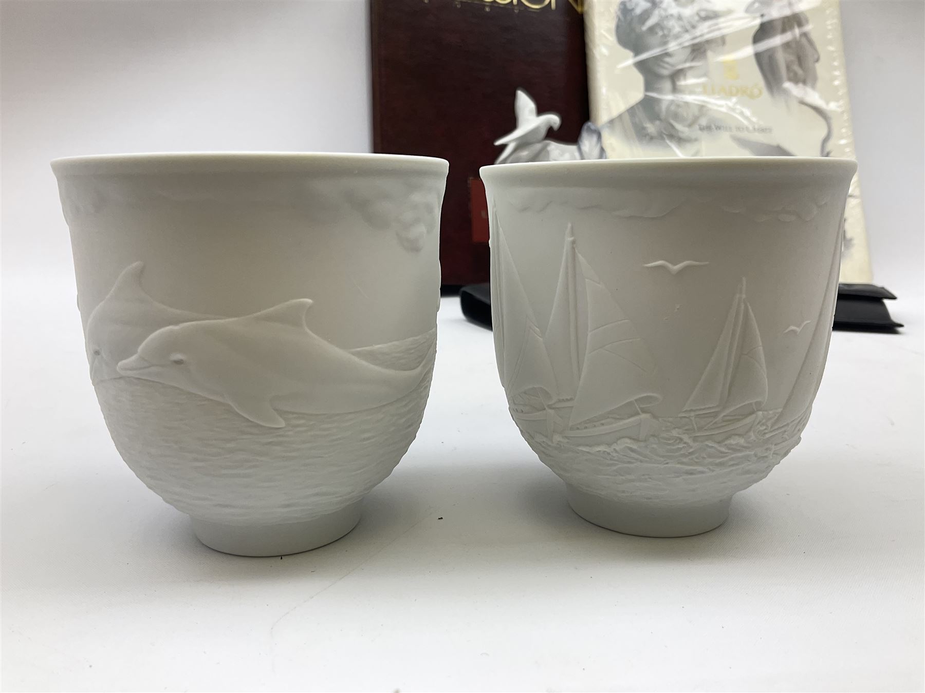 Lladro Collectors Society items, comprising of The Will to Create book, two candle holders; Sailing the Sea no 17665, Dolphins at Play no 17666, Plaque Bringing Us Together, key fob, leather wallet and a members joining pack with plaque, all in original boxes  