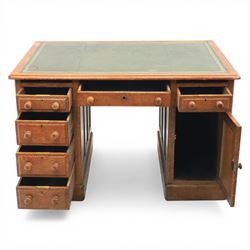 20th century oak compact pedestal desk, tooled green leather inset top, above a single frieze drawer, with a bank of four graduated drawers and a drawer and cupboard, panelled sides raised on castors