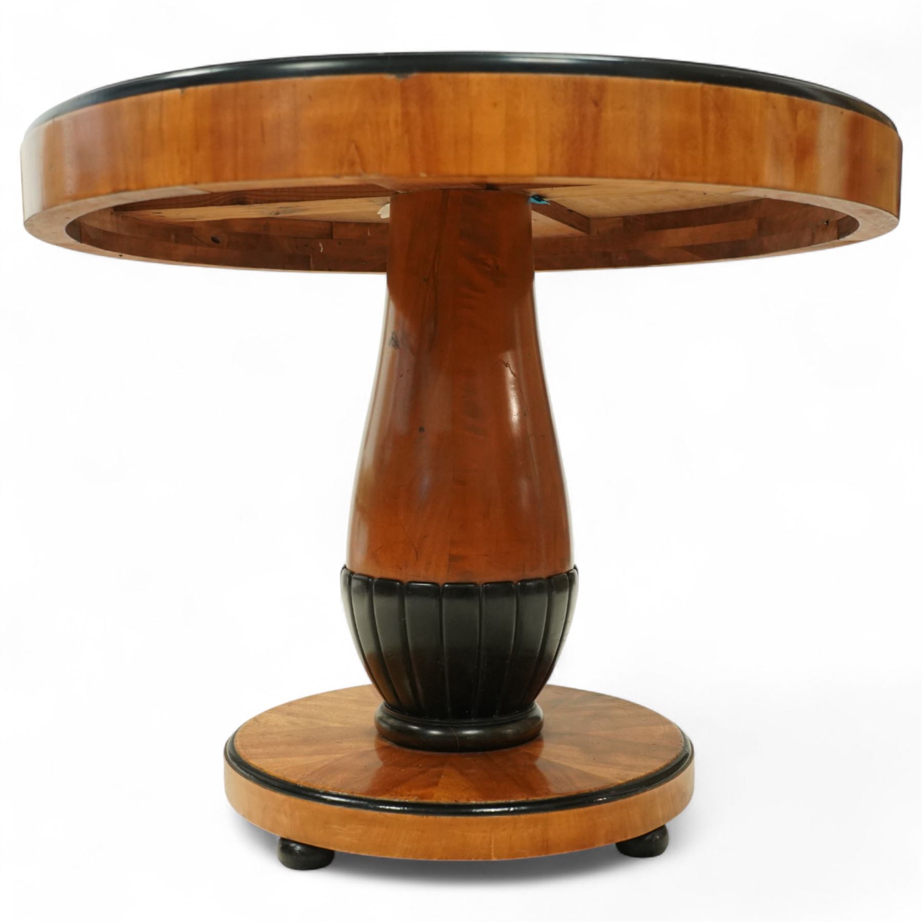 Mid-20th-century Biedermeier-style ebonized and satinwood pedestal table, quarter-veneered circular top with ebonized edge above a tapered baluster quarter-lobed column, raised on a circular plinth base, D87xH70cm, together with two matching upholstered spoon back chairs W45xD47xH87cm