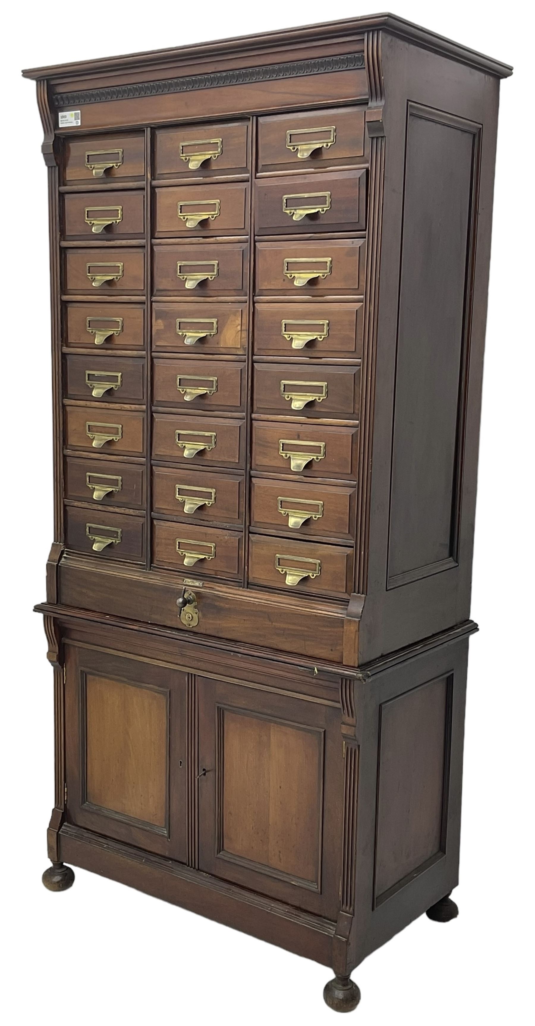 The Shannon Limited - late Victorian walnut filing cabinet, fitted with twenty-four small filing drawers, each with brass handle with label holder, fluted uprights, double cupboard below enclosed by two panelled doors, on turned feet, with brass plaque inscribed 'The Shannon, Limited, Ropemaker St. London, E.C.'