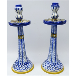  Gouda for Liberty & Co. pair pottery candlesticks of lobed tapering form with circular drip trays and double gourd shaped sconces, painted in underglaze blue with stylized motif and yellow bandings, H38.5cm    