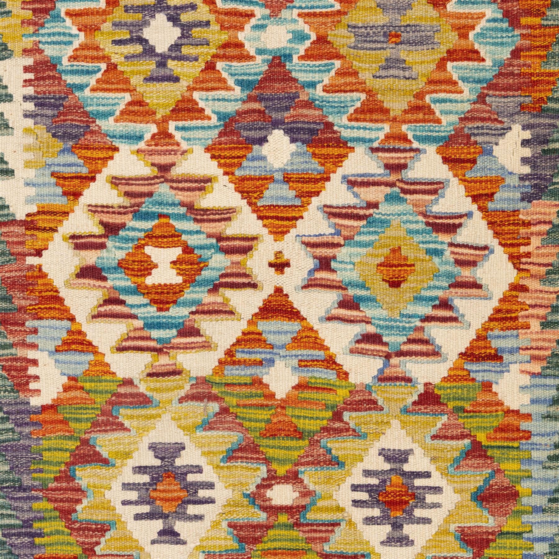 Chobi flatweave kilim runner with a repeating stepped diamond medallion design in live green, rust, teal, purple, and ivory, framed by chevron and geometric borders