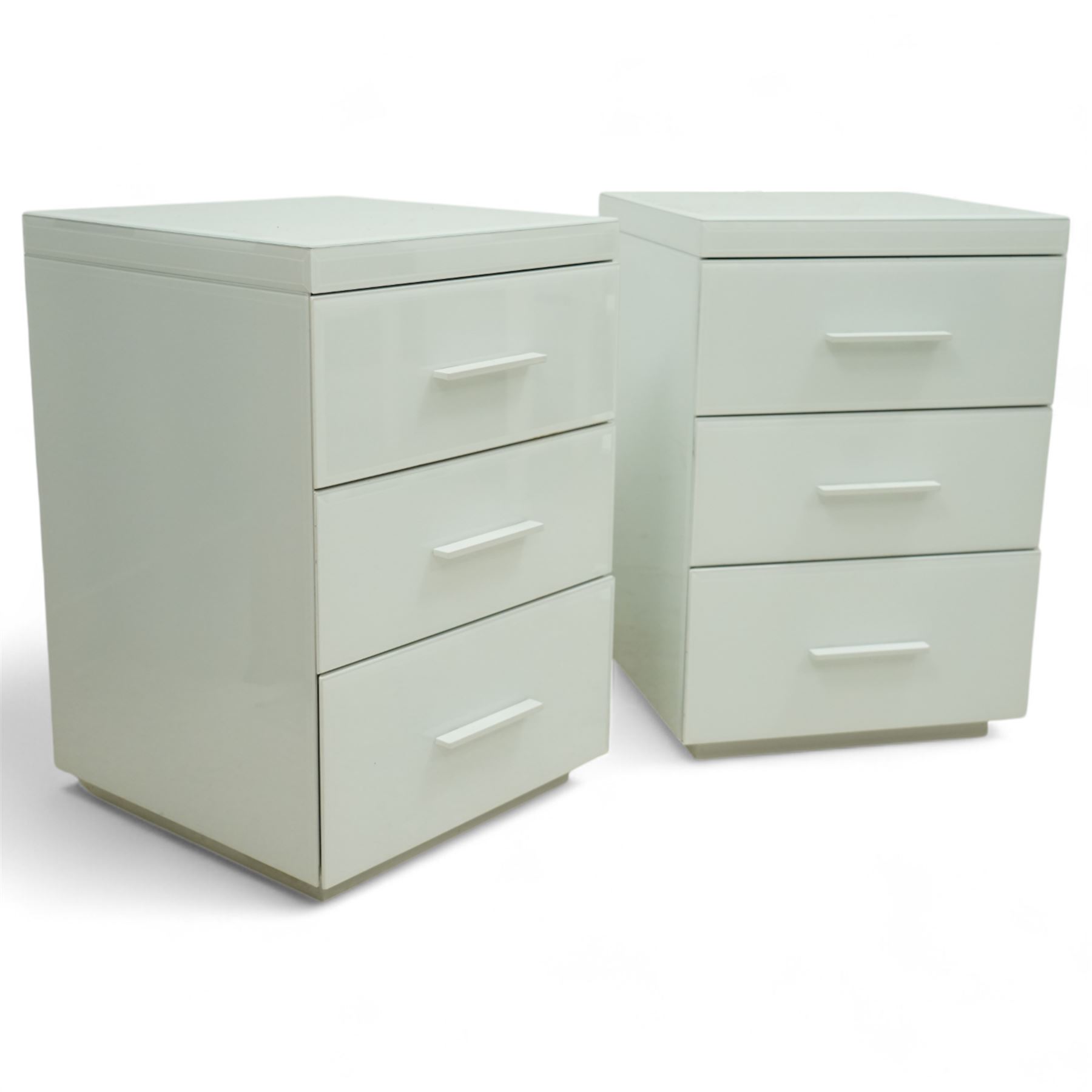 Pair of contemporary white and glass bedside chests, with square top over three drawers with integrated handles, plain sides and plinth bases