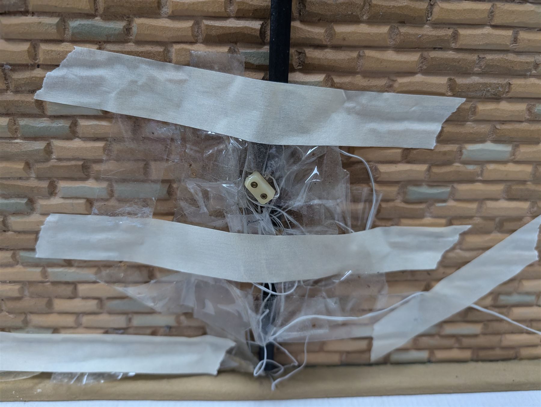 1:24 scale stone effect three-storey cottage dolls house, with green arched door and lattice effect windows, decorated to the interior with wooden floors, wired lighting and fire places, H45cm, W57cm, D26cm