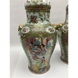Pair of 19th century Chinese Famille Rose vases and covers, each of baluster form with twin gilt lion mask ring handles to shoulders, the flattened domed covers with gilt temple lion finials, each decorated with alternating reserves of bijin and attendants, and birds and butterflies amongst blossoming peonies, against a gilt ground profusely decorated with stylised scrolls, H32.5cm