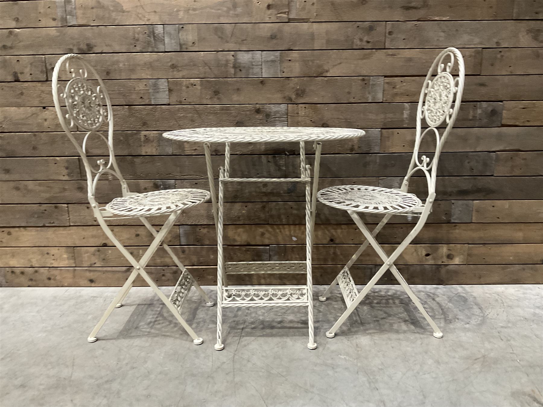 Cast metal bistro set including ornate oval garden table and two matching chairs