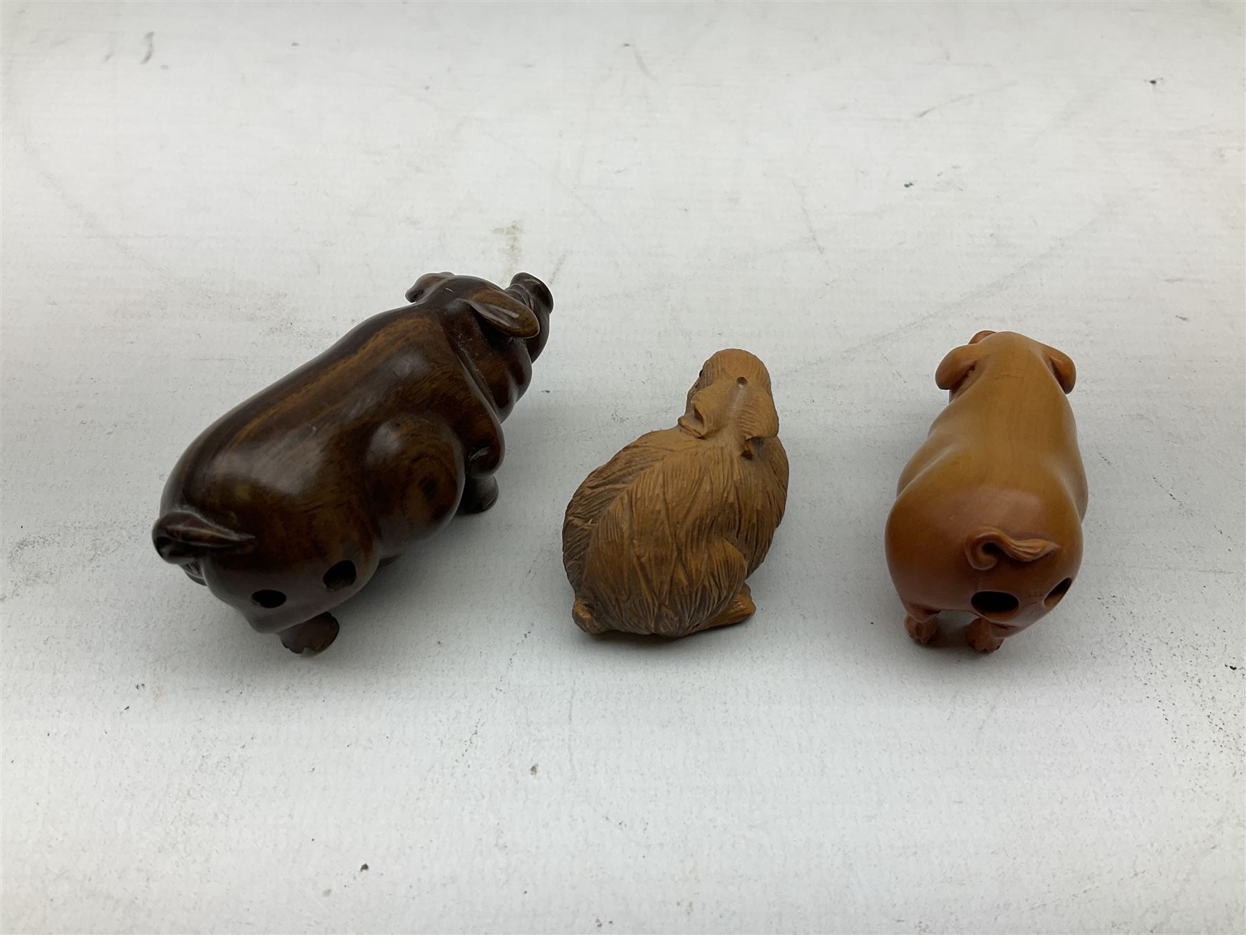 Group of ten Japanese netsukes, comprising eight carved wooden examples, and two ivorine examples, of various form, examples modelled as pigs, owl, mouse with tortoise upon its back, birds, rabbit, etc. 