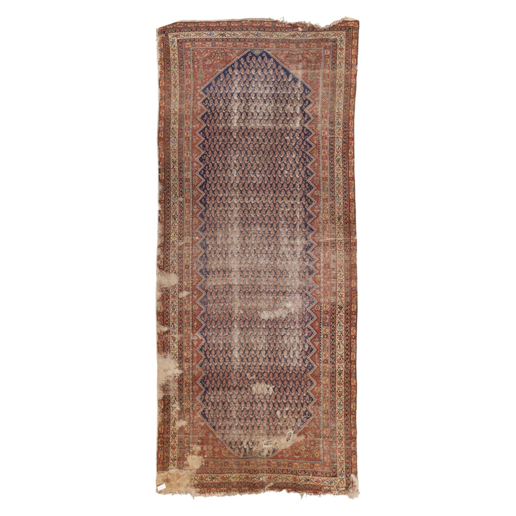 West Persian Kurdish vintage carpet, indigo field decorated with an all-over repeating boteh design arranged in diagonal rows framed by angular spandrels and enclosed by multiple geometric borders in a palette of indigo blue, madder red, soft green and ivory