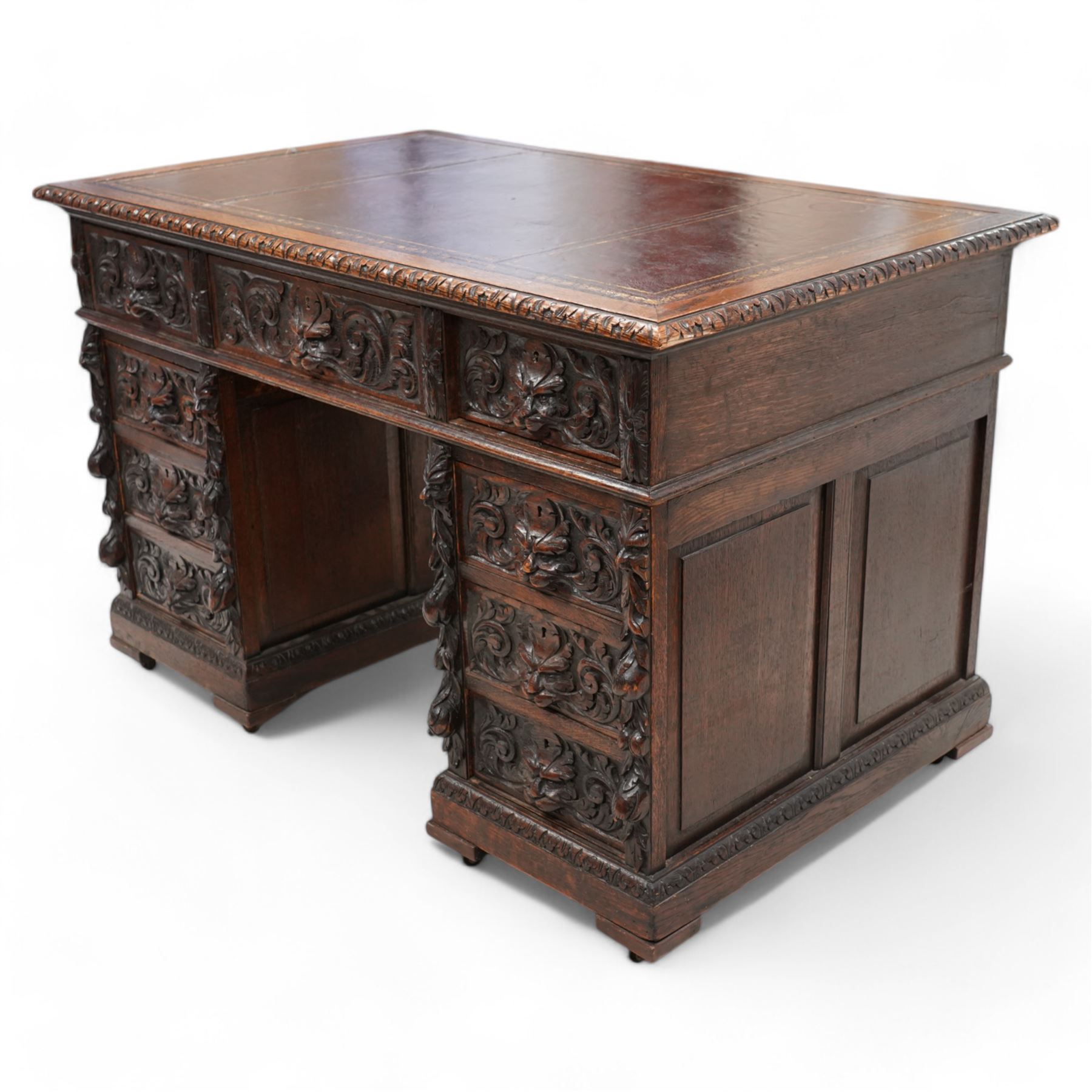 Victorian carved oak twin pedestal desk, moulded and foliate carved rectangular top with leather inset, fitted with nine drawers, each carved with scrolling foliage and lion mask handles, on skirted base 