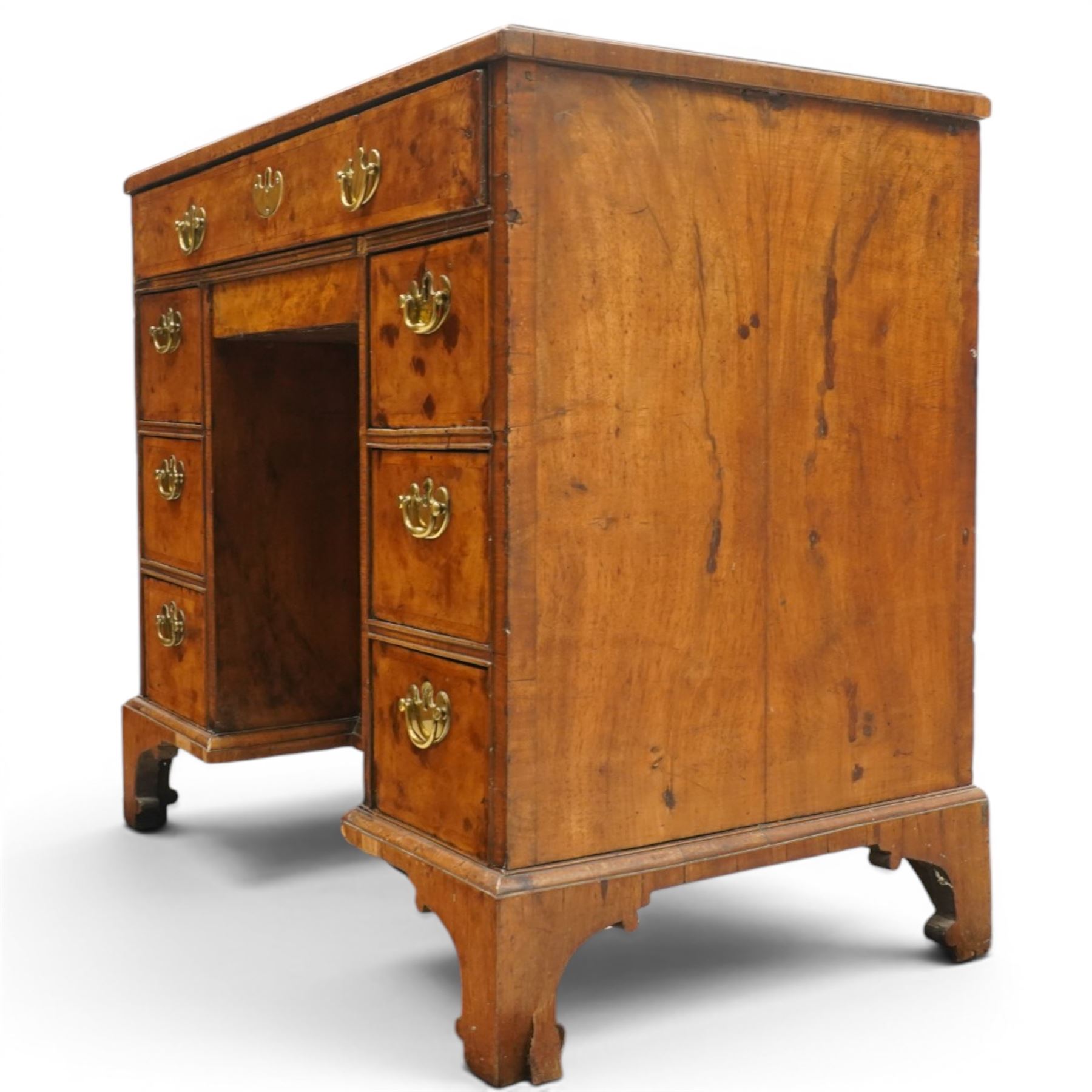 George II figured walnut kneehole desk, the rectangular book-matched veneer top with feather and cross-banding, fitted with single frieze drawer over a short drawer and central recessed cupboard, flanked by three drawers to each side, lower moulded edge on bracket feet