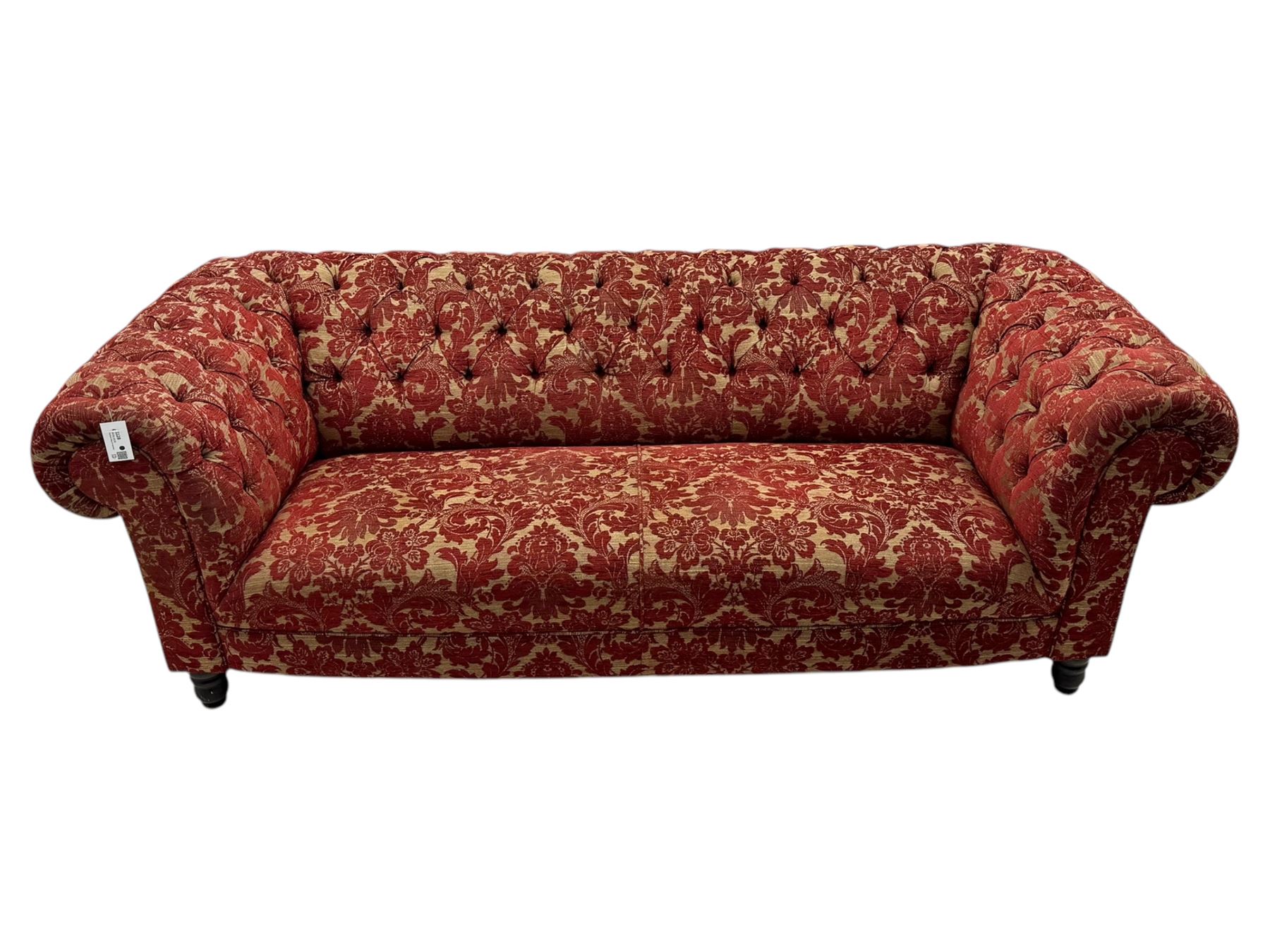 Late 20th century upholstered Chesterfield sofa, in red damask floral fabric, with deep buttoned back and arms, scrolled arms at equal height to back, on turned front supports