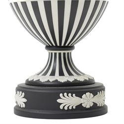 Wedgwood 20th century 'Dancing Hours' jasperware urn, the upper section decorated with a single band of neoclassical maidens in white to a black basalt ground, rising from a circular plinth decorated with foliate motifs, complete with cover with acorn finial, stamped 'Wedgwood Made in England', H25cm 