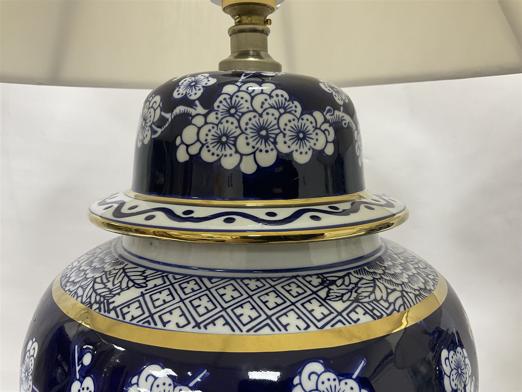 Pair of blue and white table lamps, each of baluster form, decorated with prunus blossom, within stylised borders, raised upon circular gilt base, excluding fittings H48cm