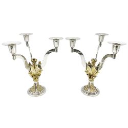 Pair of modern limited edition silver three branch candelabra, commemorating the marriage of HRH Prince Charles and Lady Diana Spencer, replicas of the St Paul's Cathedral candelabra, the three gilt branches each supporting a fluted candle holder and united by a crown containing the Prince of Wales feathers, upon a parcel gilt stem, with three griffins, each holding crested shields, above parcel gilt flower heads cascading to a ciruclar foot, limited edition no. 119 & 120/400, hallmarked Henry Miller for Aurum, London 1981, H22cm