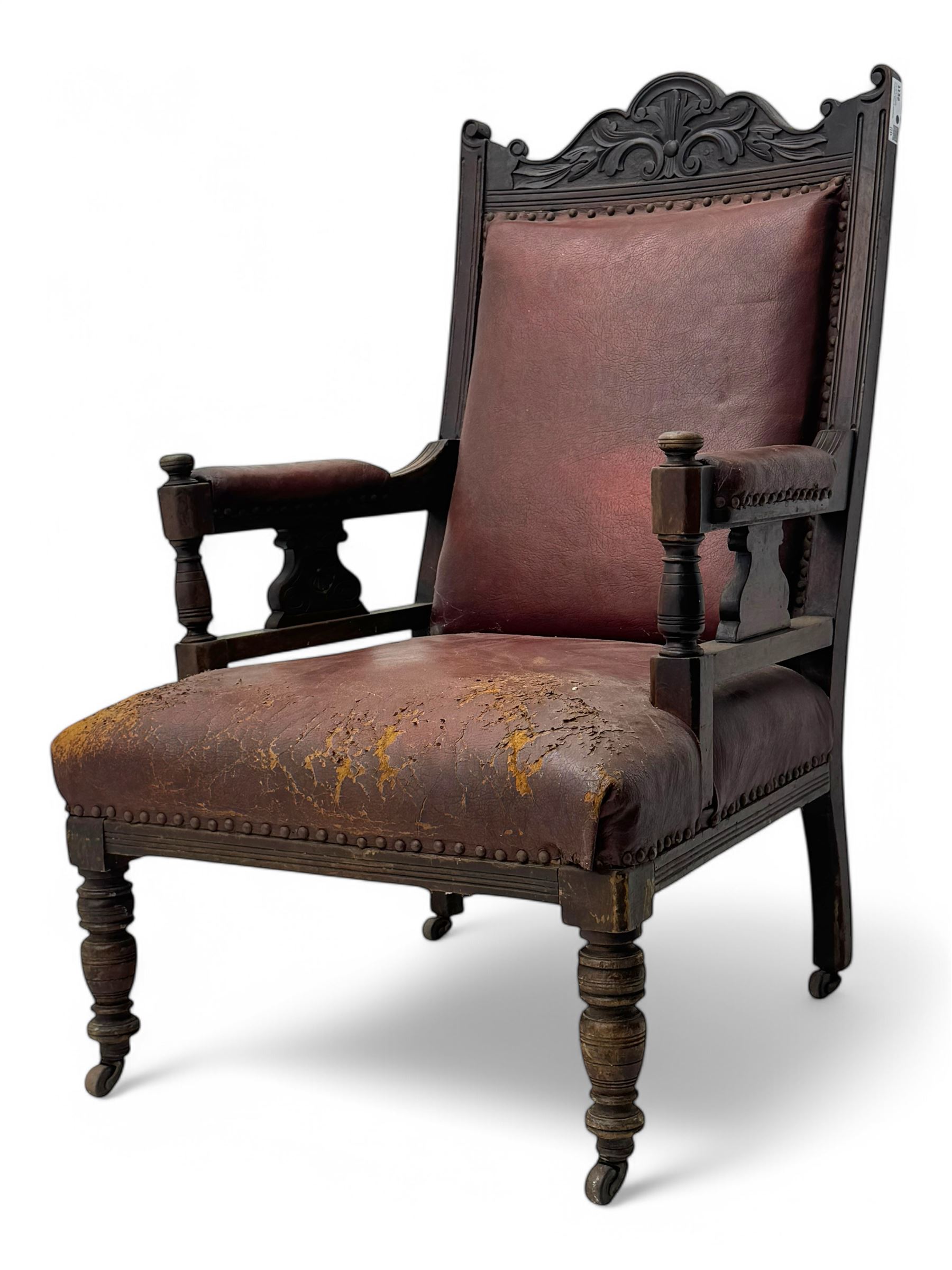 Victorian walnut framed armchair, shaped pediment carved with scrolling foliage, upholstered in leather, on ring turned front feet