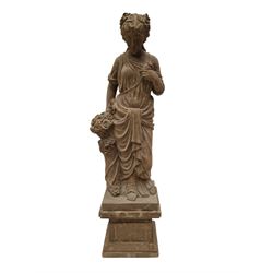 Hand carved stone Neoclassical figure of the Roman goddess Flora, her hair pinned with roses, draped in a toga, holding a basket of flowers in her right hand, raised on a stepped square plinth base 