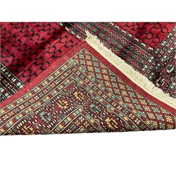 Tekke Ensi crimson ground rug, the quartered field decorated with candelabra motifs, multi-guarded border with repeating geometric hexagonal lozenges in blue and ivory