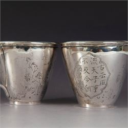 Pair of Chinese export silver teacups, both decorated with character marks, one with floral decoration, the other decorated with a bird within bamboo branches, both with indistinct maker's marks beneath, H6cm