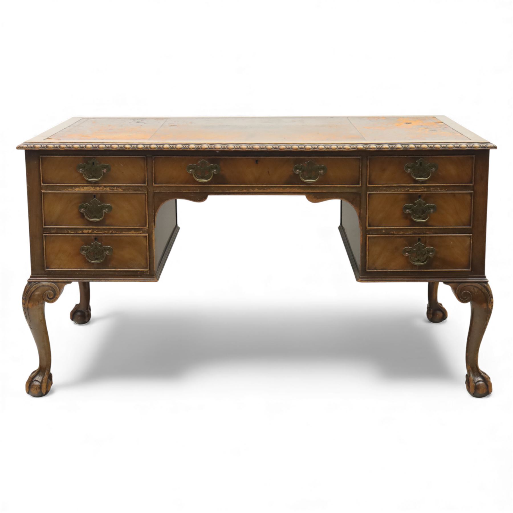 Waring & Gillow - Early 20th century mahogany desk, the leather-inset top above a shaped kneehole, central compartmented frieze drawer flanked by twin banks of of three drawers, each with brass handles, raised on cabriole legs with carved ball and claw feet (Height from floor to underside 62cm)